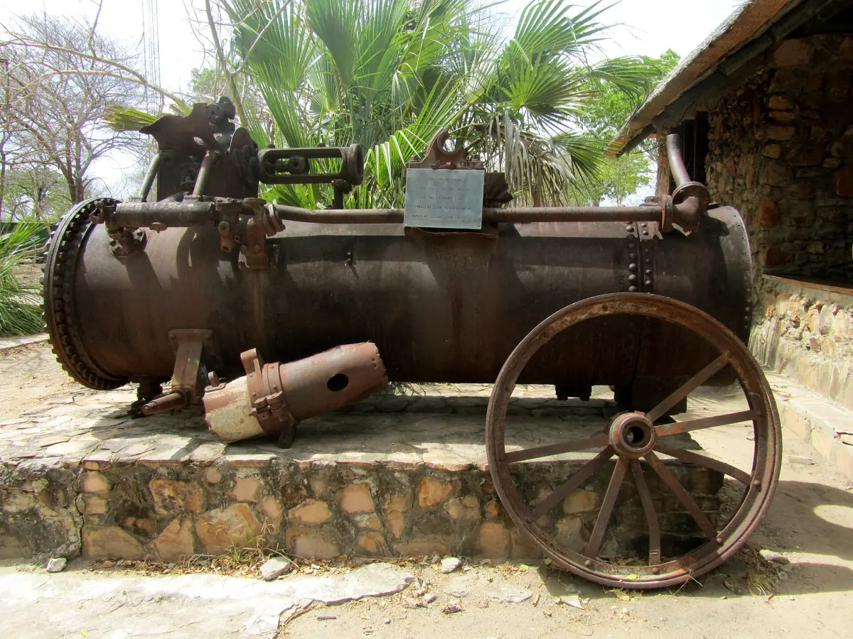 Rusting German steam engine kept as a monument beside a stone building