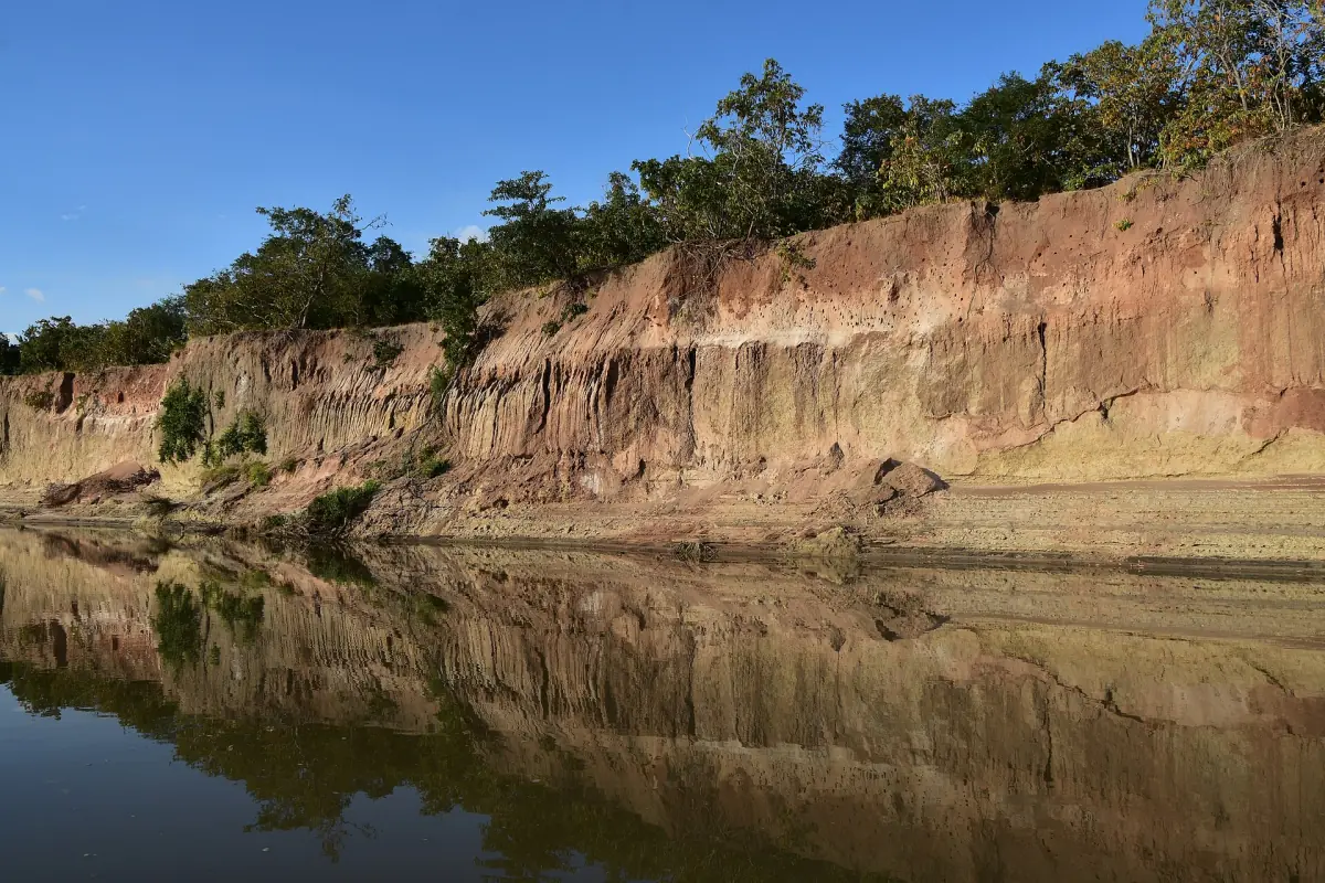 Rote Sandsteinuferwand des Rufiji, die sich im ruhigen Wasser spiegelt